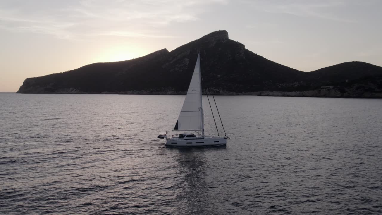 Purjehdus saaren kallioiden lähellä auringonlaskun aikaan, Dragonera, Mallorca, Espanja.