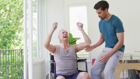 Entrenador-Masculino-Birracial-Que-Ayuda-A-Un-Hombre-Mayor-Discapacitado-A-Hacer-Ejercicio-Con-Pesas-En-El-Gimnasio