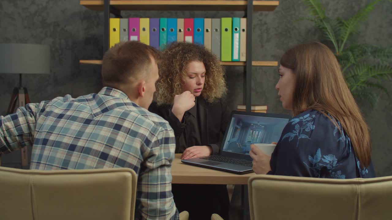 una bonita agente inmobiliaria muestra el diseño de la casa a una pareja casada.