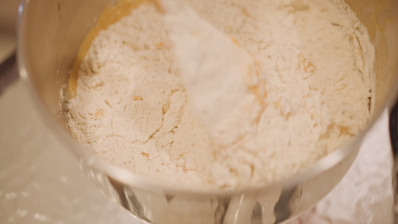 Closeup mixing pumpkin pie batter in stainless bowl, home baker gently folding flour into spiced custard, silicone spatula, warm golden lighting, measuring cup on counter, cozy harvest mood