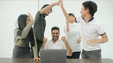 un equipo de negocios creativos casuales y diversos están trabajando duro para completar un acuerdo de negocios. celebran cuando descubren que han tenido éxito