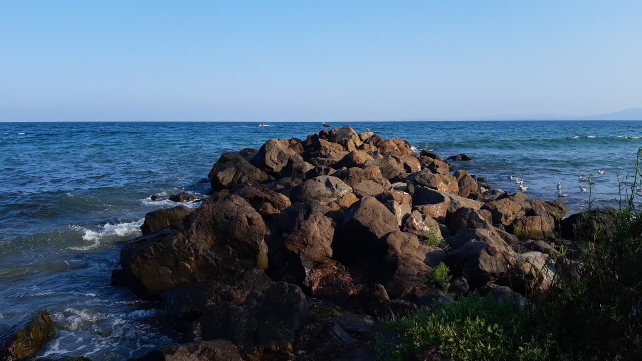 Bølger slår ind mod en bunke sten på stranden