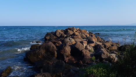 waves crash on a pile of rocks on the beach