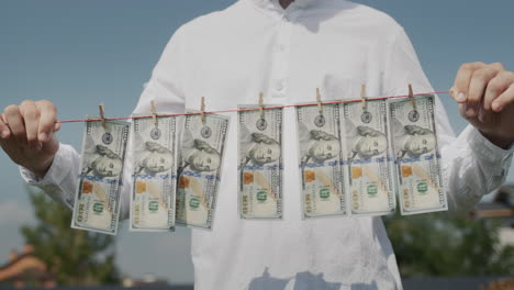 a man holds a clothesline in his hands, on which banknotes hang. money laundering concept