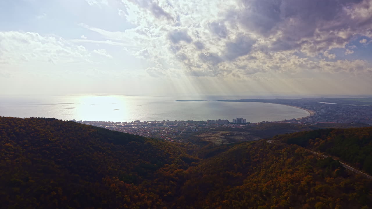 Vista maestosa sulle montagne che si affacciano sul mare scintillante e sulla costa estesa sotto un cielo drammatico al tramonto