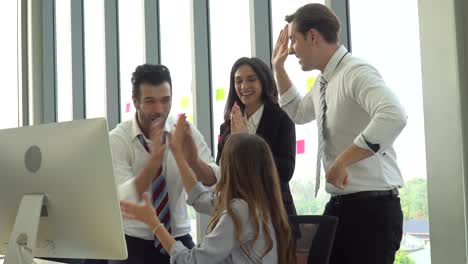 grupo de personas de negocios que se reúnen con la computadora emocionada levantan la mano para celebrar el éxito juntos en la oficina. conferencia de equipo de marketing tormenta de ideas. trabajador de pie y hablando con su colega.