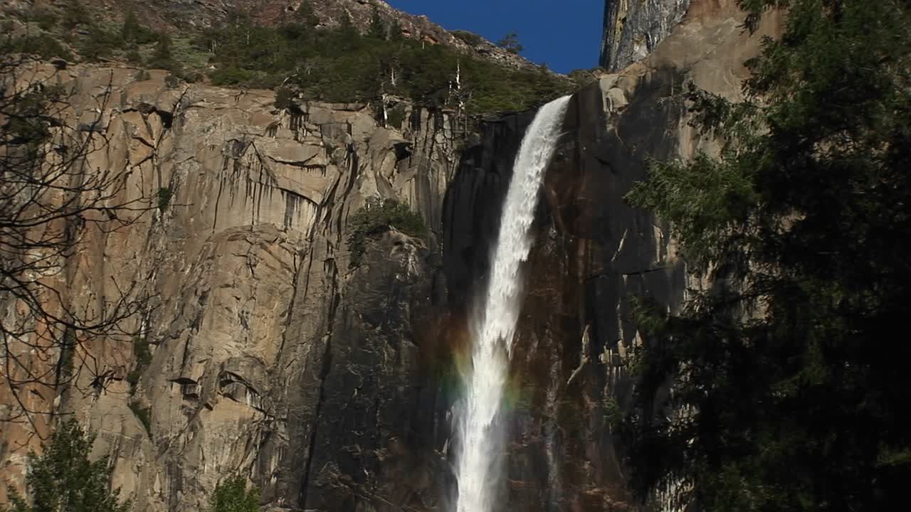 una cascada que fluye rápidamente destaca un acantilado rocoso empinado