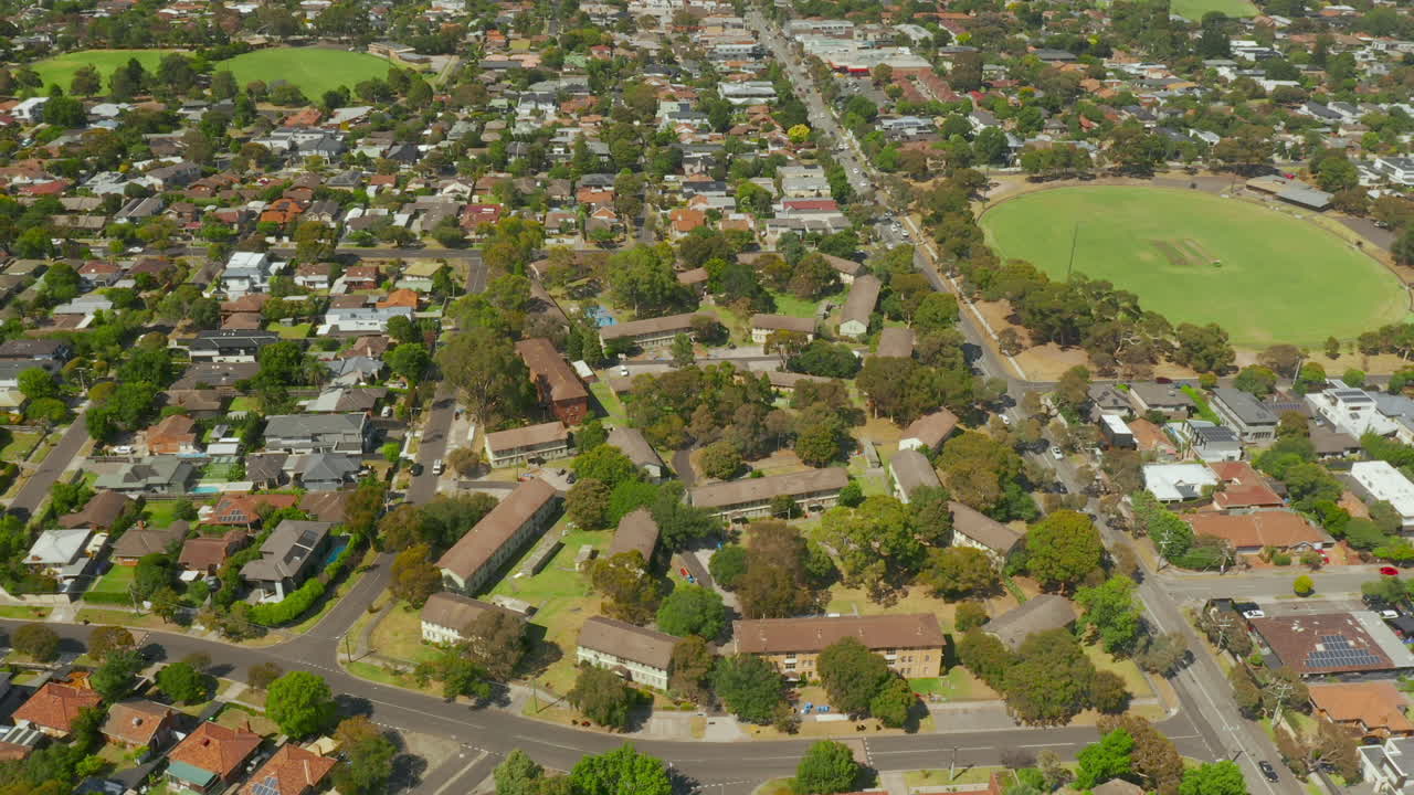 vista aérea que revela casas suburbanas y flujo de tráfico dinámico en la carretera cercana