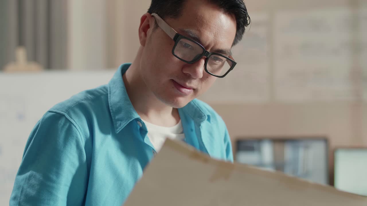 Close Up Of Asian Man Engineer With A Laptop Looking At Blueprint While Working At The Office