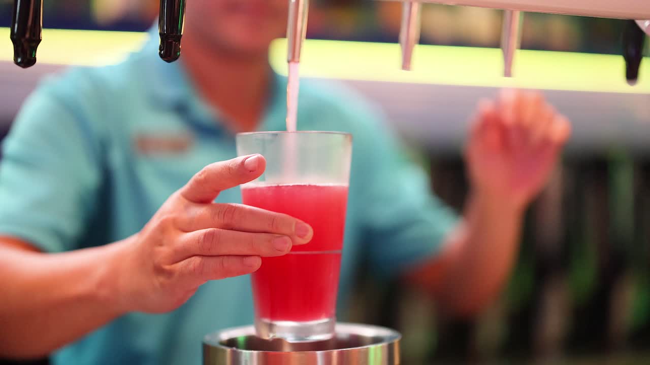 바텐더가 프에서 은 음료를 유리잔에 부어 넣습니다.