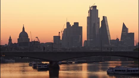 morning sunrise behind st paul's cathedral and the city of london with waterloo bridge in foreground