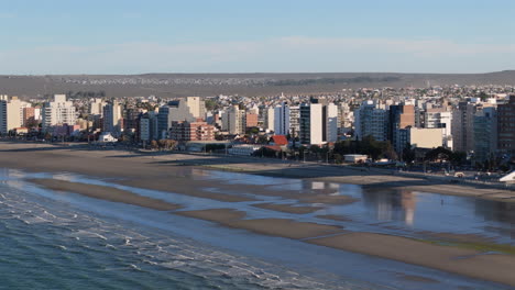 amazing drone view of the coastal city skyline overlooking serene ocean waters, patagonia chubut, puerto madryn, argentina.