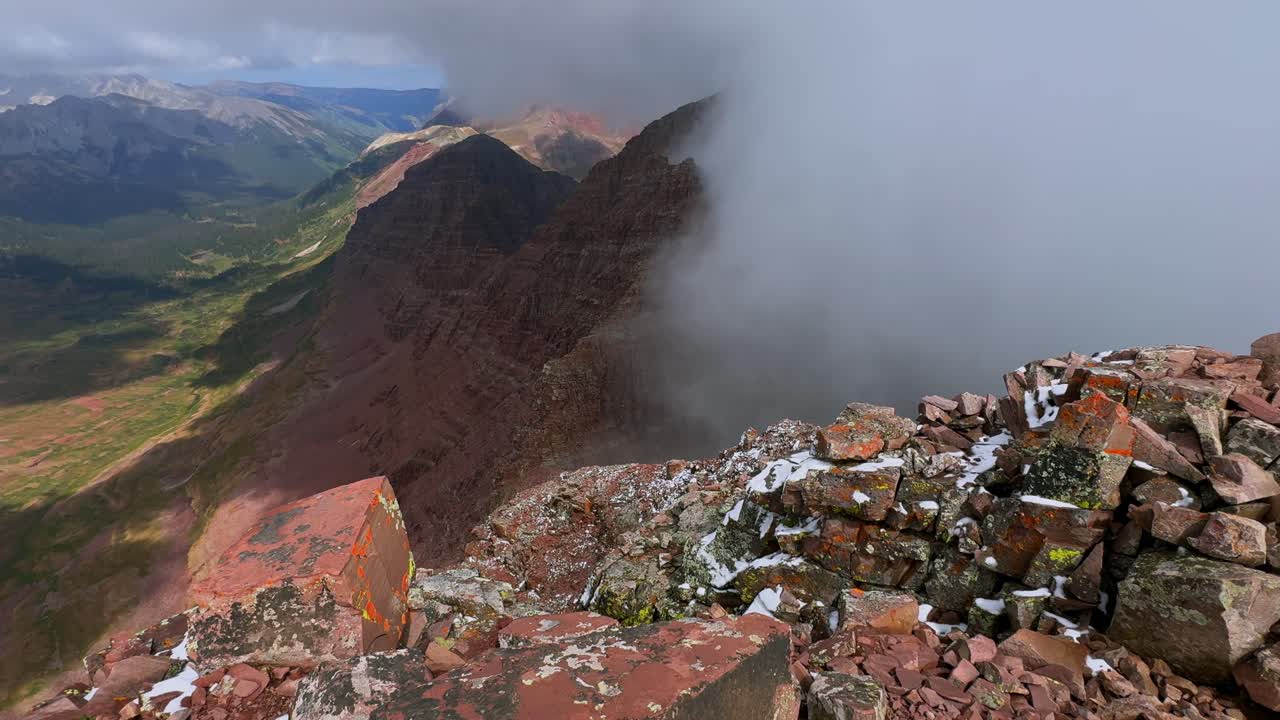 North Maroon Peak dark cloudy thick dense fog snow dusting Aspen Snowmass Maroon Bells Wilderness valley Colorado summer panoramic view fourteener Elk Range Rocky Mountains rugged terrain pan left