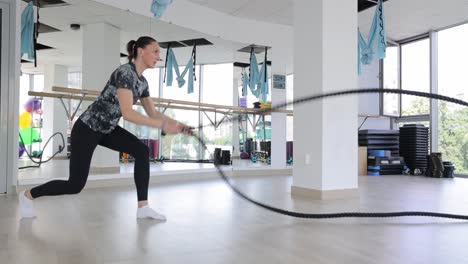 woman working out with battle ropes in a gym