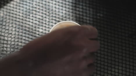close-up of a person's hand gently removing a paper filter from a coffee cup, revealing foam inside. the action highlights attention to detail in coffee preparation, with focus on the drink's texture