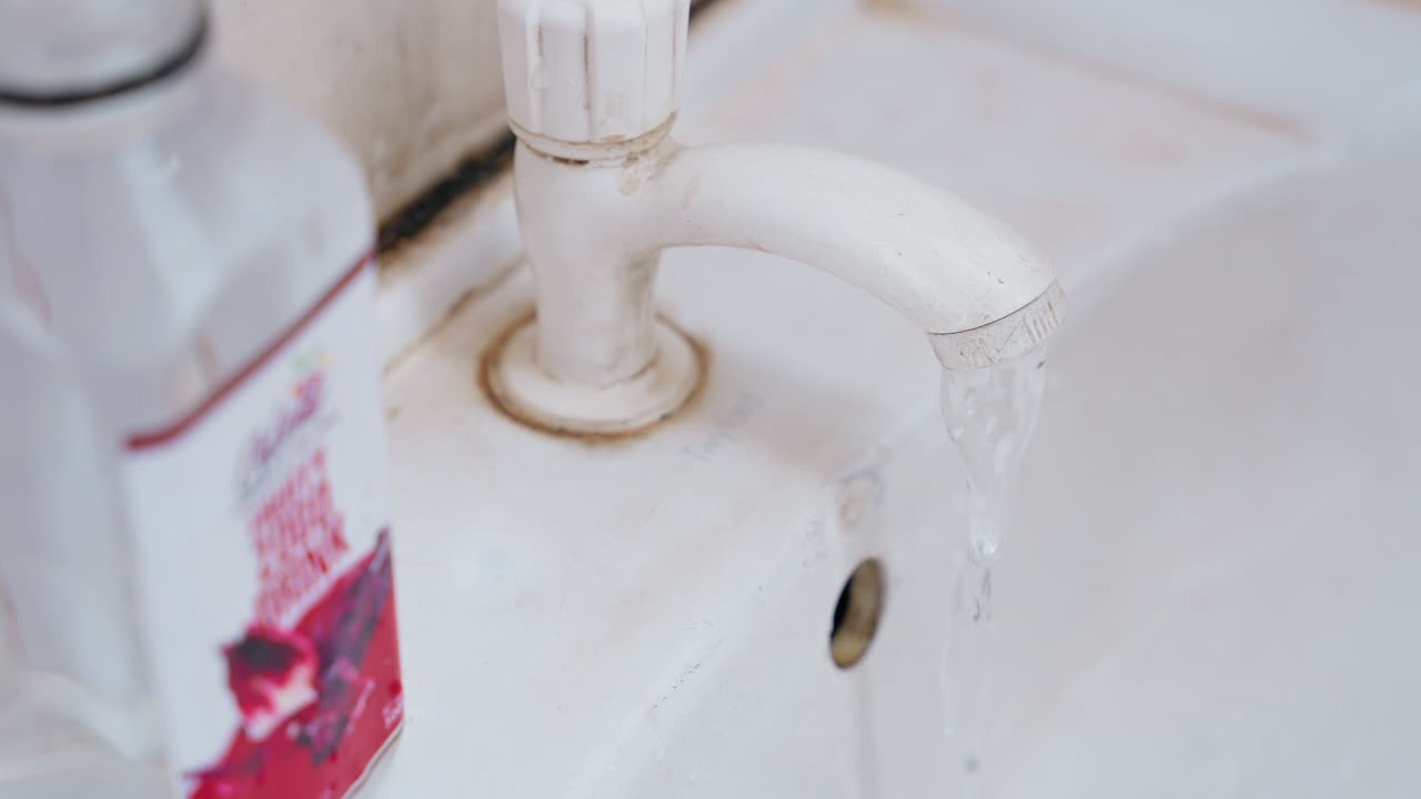 Household hygiene scene. Careful rinsing at domestic sink. Porcelain sink with soft lighting during cleaning routine. Peaceful setting of household chores involving washing and sanitation