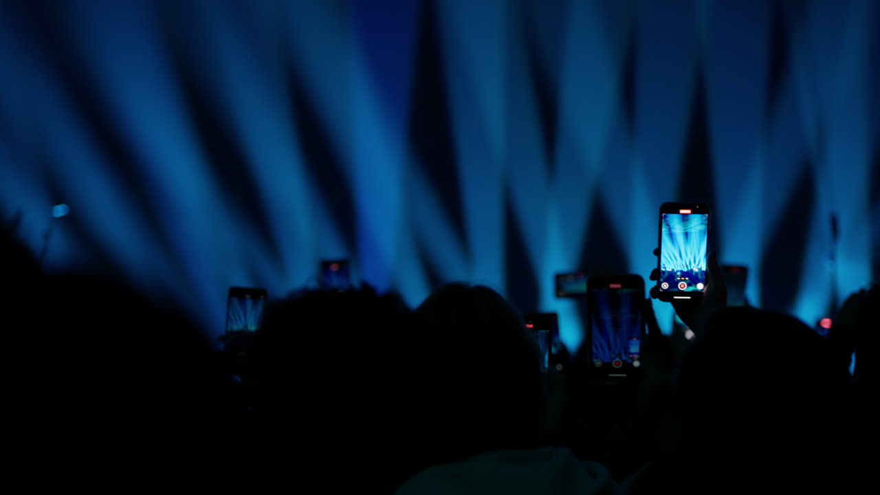Audience Recording Live Concert with Smartphones and Blue Stage Lights