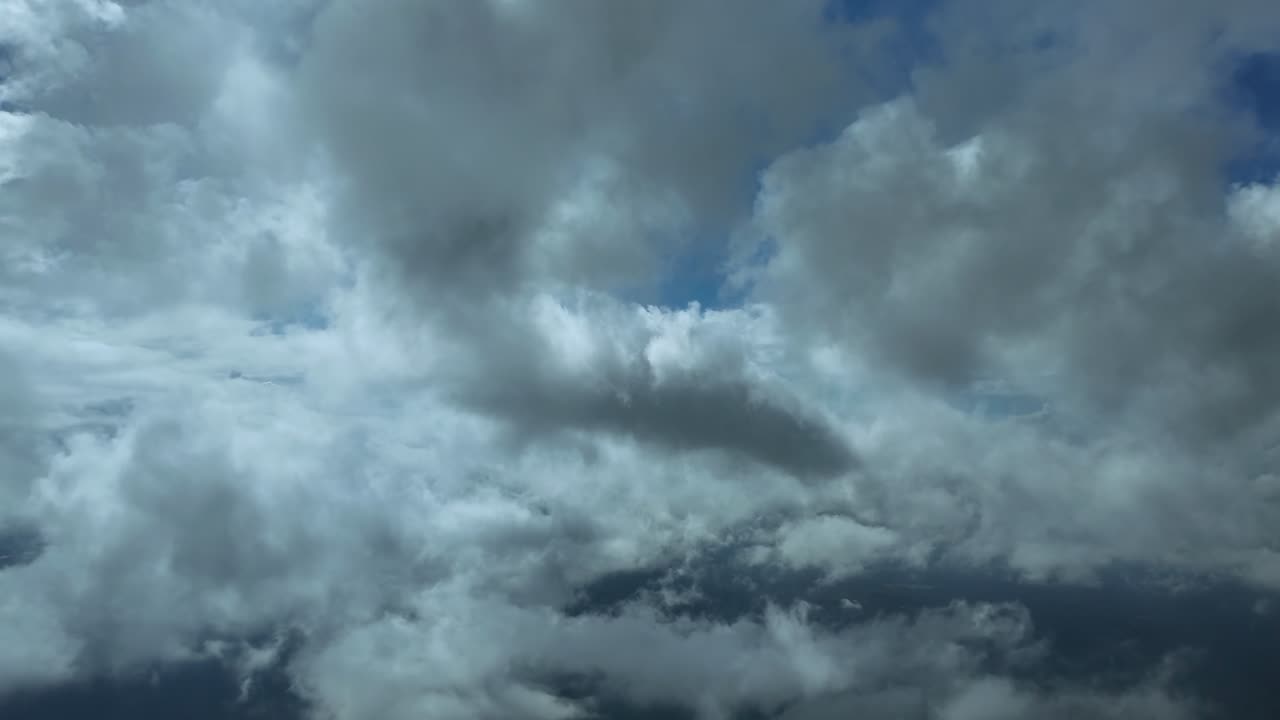 Immersive pilot’s perspective from the cockpit of a jet flying peacefully through multi-layer ethereal clouds hanging in a blue sky