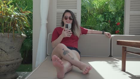 front view of a woman relaxing under the shade while using her cellphone during a sunny morning