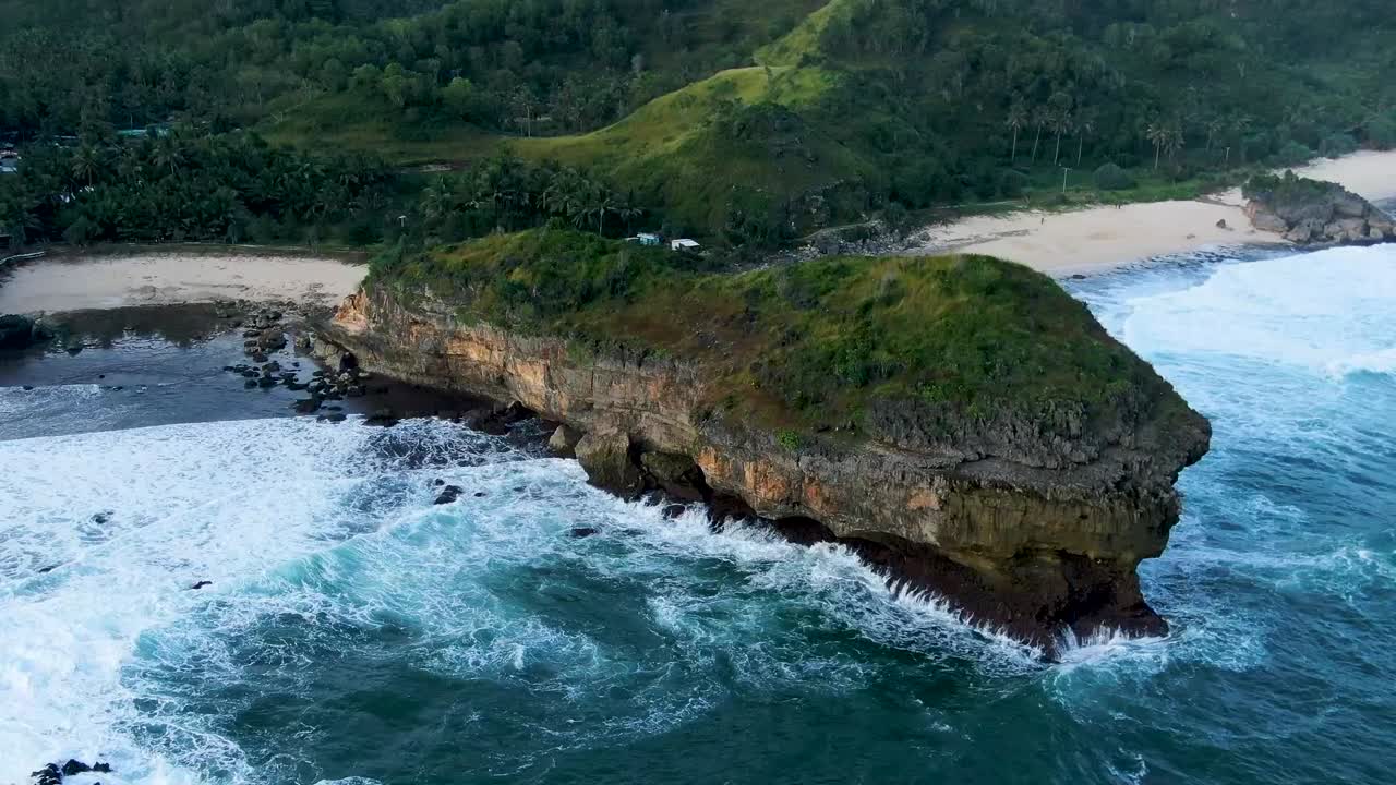 Majestic rock hit by ocean wave on Kasap beach, Java, Indonesia aerial view