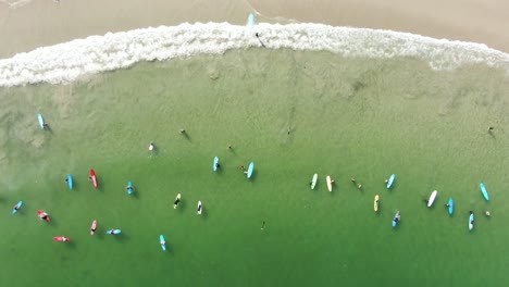 Surfers-and-colorful-surfboards-in-Hong-Kong-beach,-Aerial-view