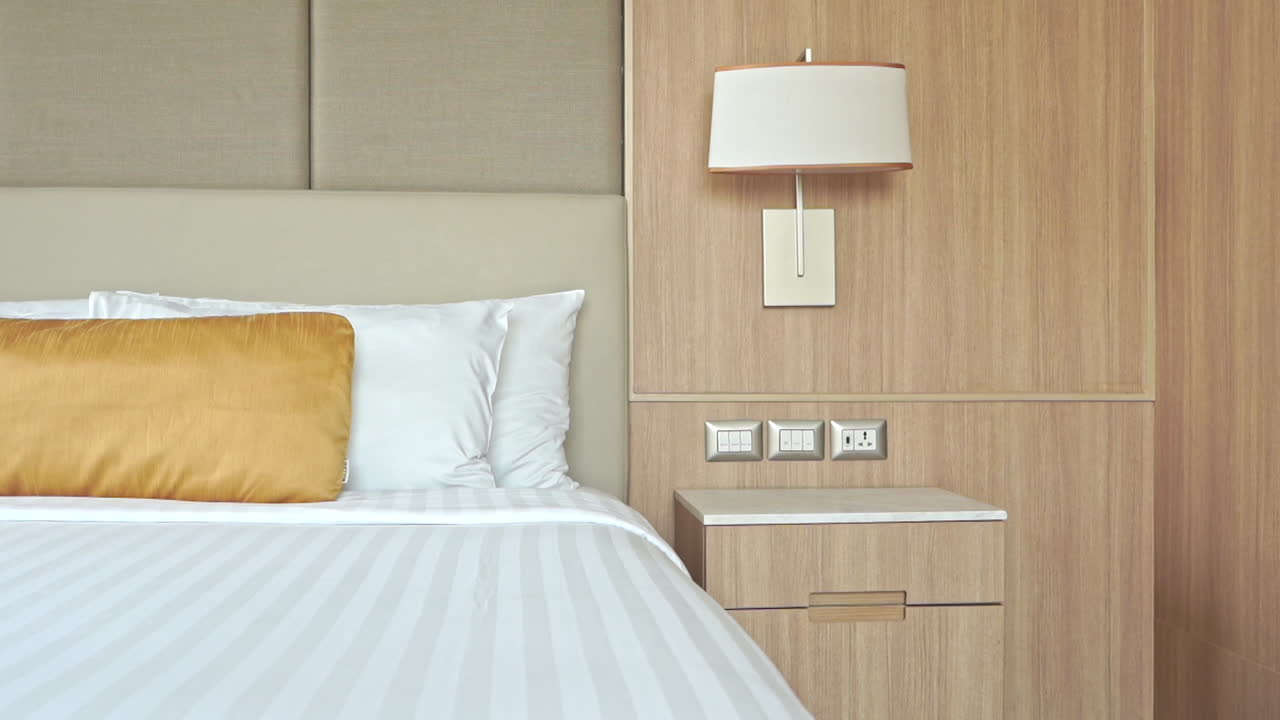 Camera d'albergo moderna vuota e letto con biancheria bianca, panoramica lenta a sinistra