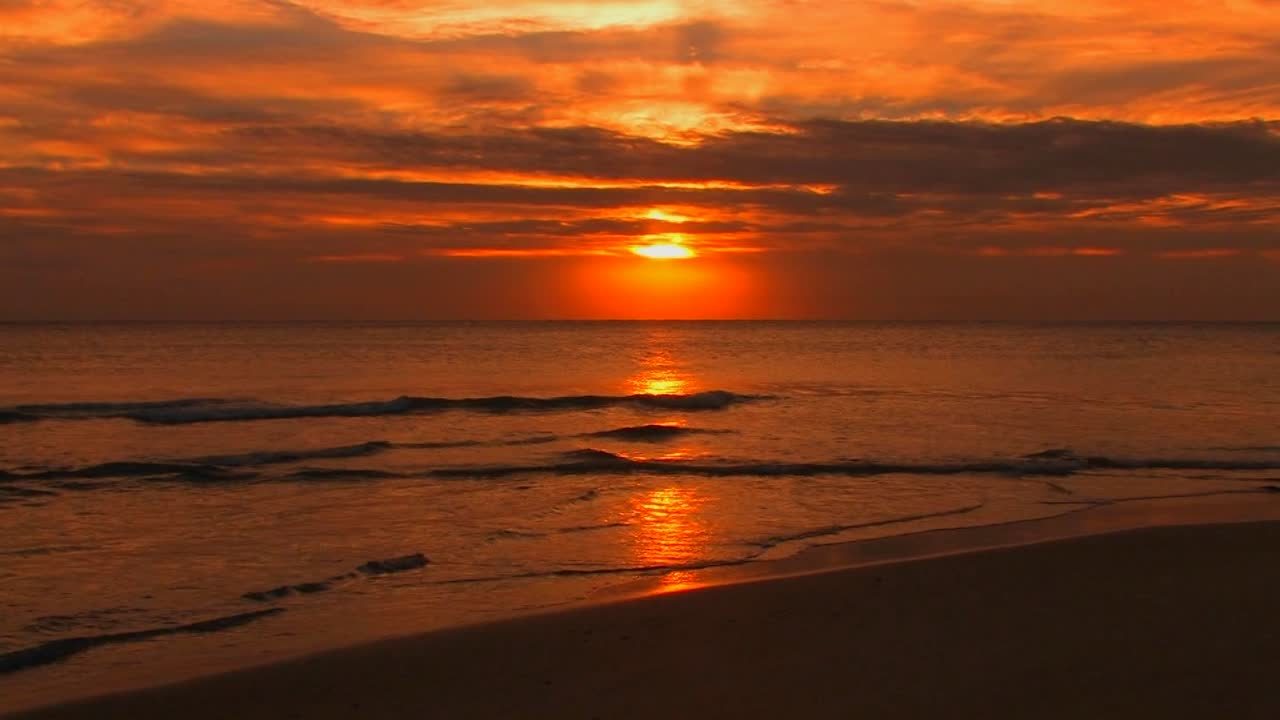 las olas de la playa se rompen lentamente durante la puesta de sol