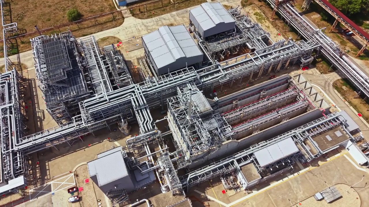 Grande impianto industriale con molteplici condotte e strutture visto dall'alto di giorno