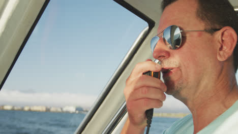 rear view of a caucasian man on boat using a walkie-talkie