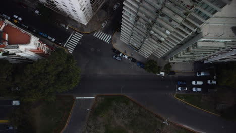 The-drone-flies-up-and-circles-over-an-empty-intersection,-street-and-residential-high-rise-buildings,-traffic-during-the-day