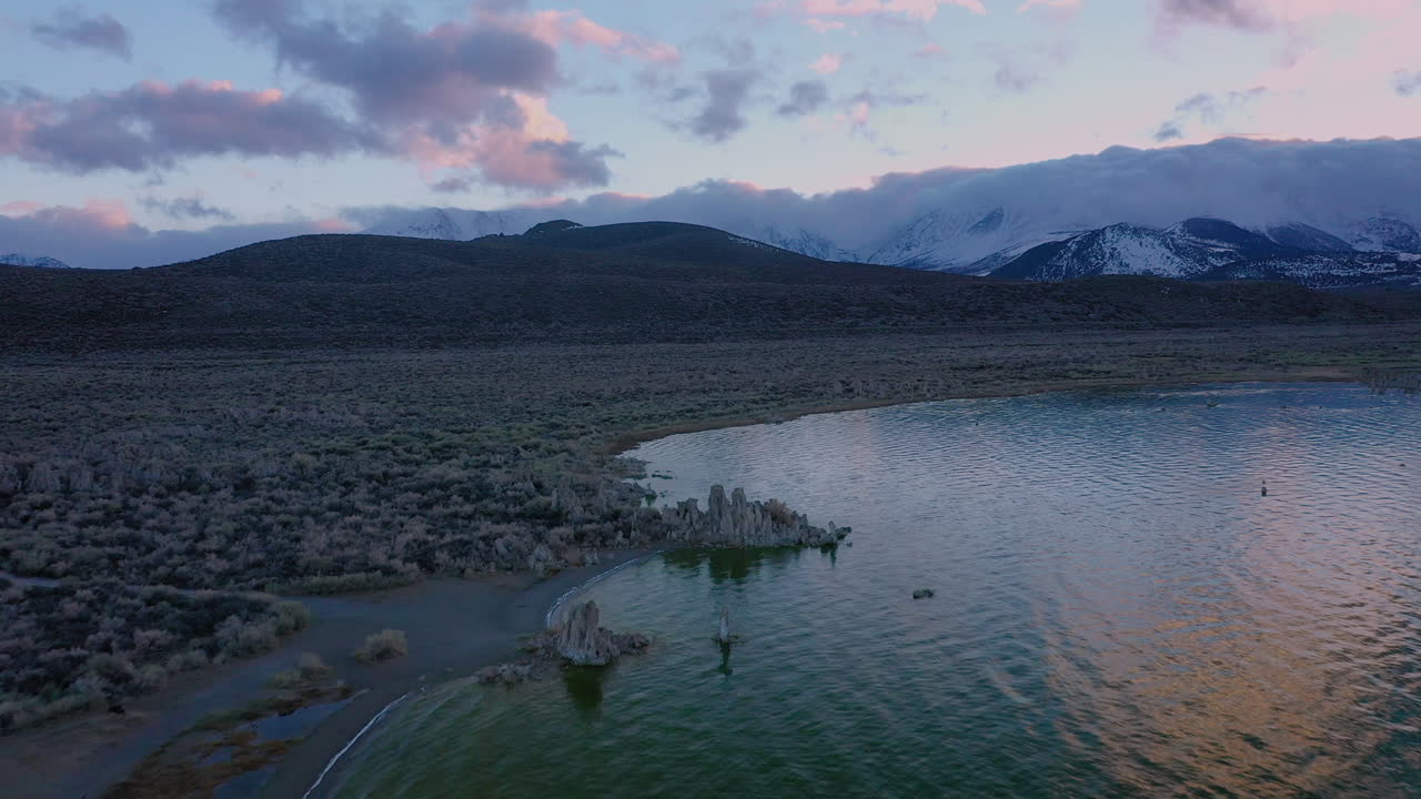 Beautiful drone footage of Mono Lake, California, during a dramatic sunset in winter, Snow-covered mountains of Eastern Sierra Nevada in the background