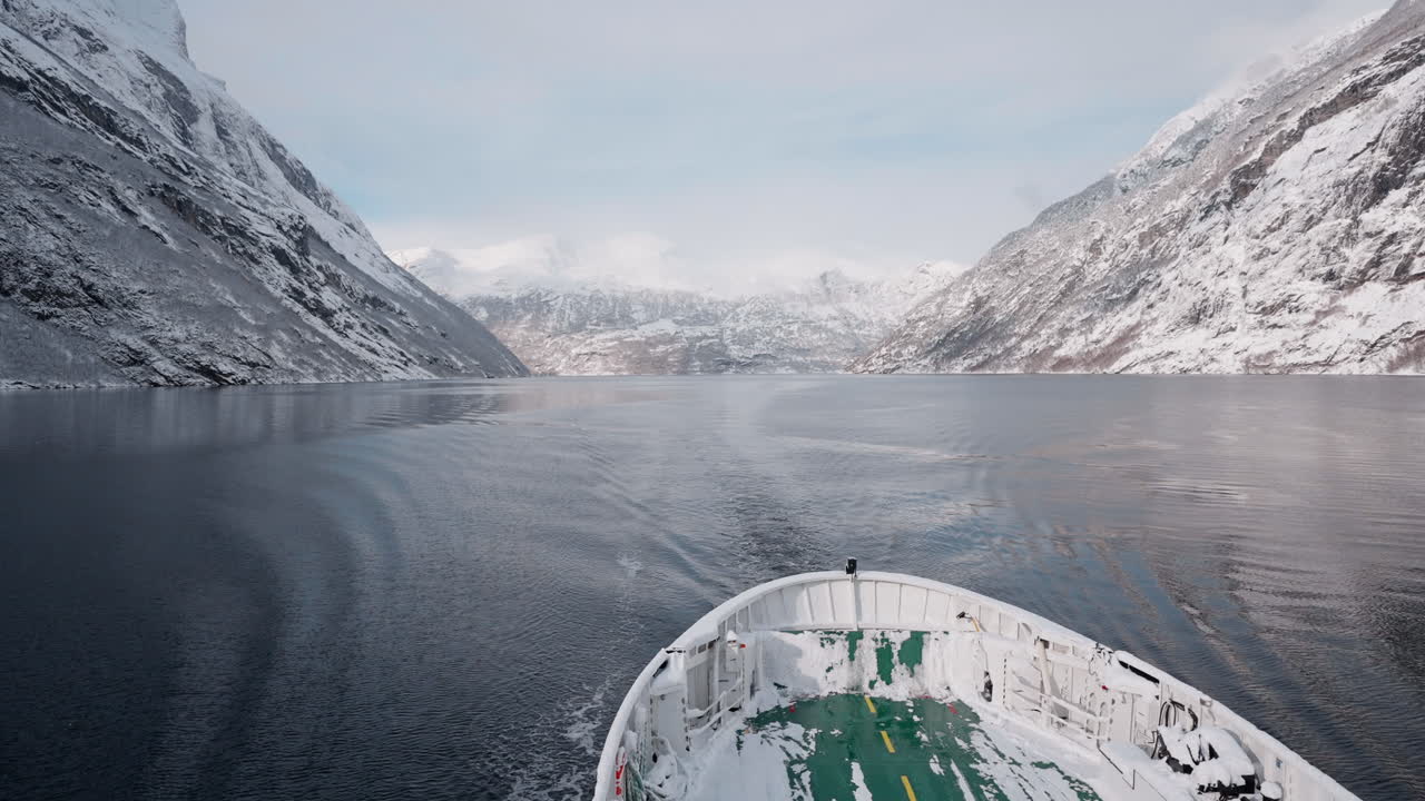 노르웨이의 geirangerfjord에서 눈 인 산과 매혹적인 피오르드 전망을 가진 겨울 페리 보트 타기의 느린 동작