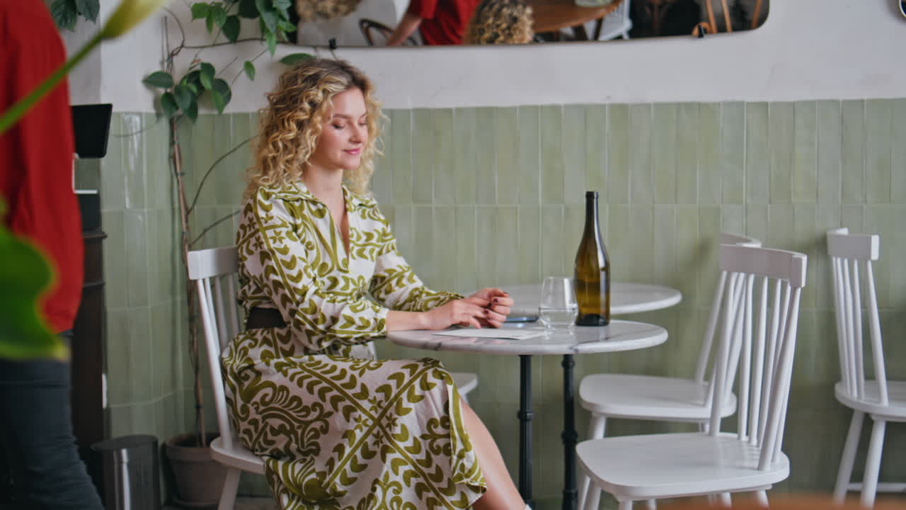 Young waitress taking order from relaxed blonde sitting cozy cafe. Smiling woman