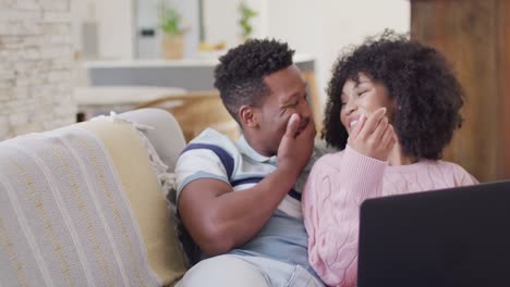 Happy-african-american-couple-using-laptop-together-in-living-room