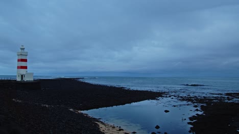 Pan-from-calm-sea-to-a-picturesque-old-lighthouse-in-Gardur,-Iceland