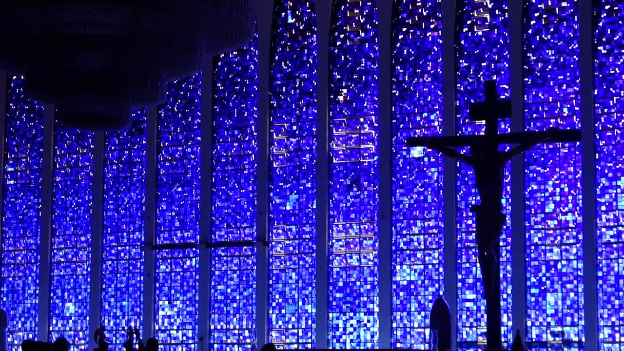 large unlit glass chandelier and cross in the background of Sanctuary of Saint John Bosco, interior view.