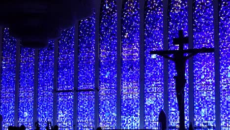 large unlit glass chandelier and cross in the background of sanctuary of saint john bosco, interior view.