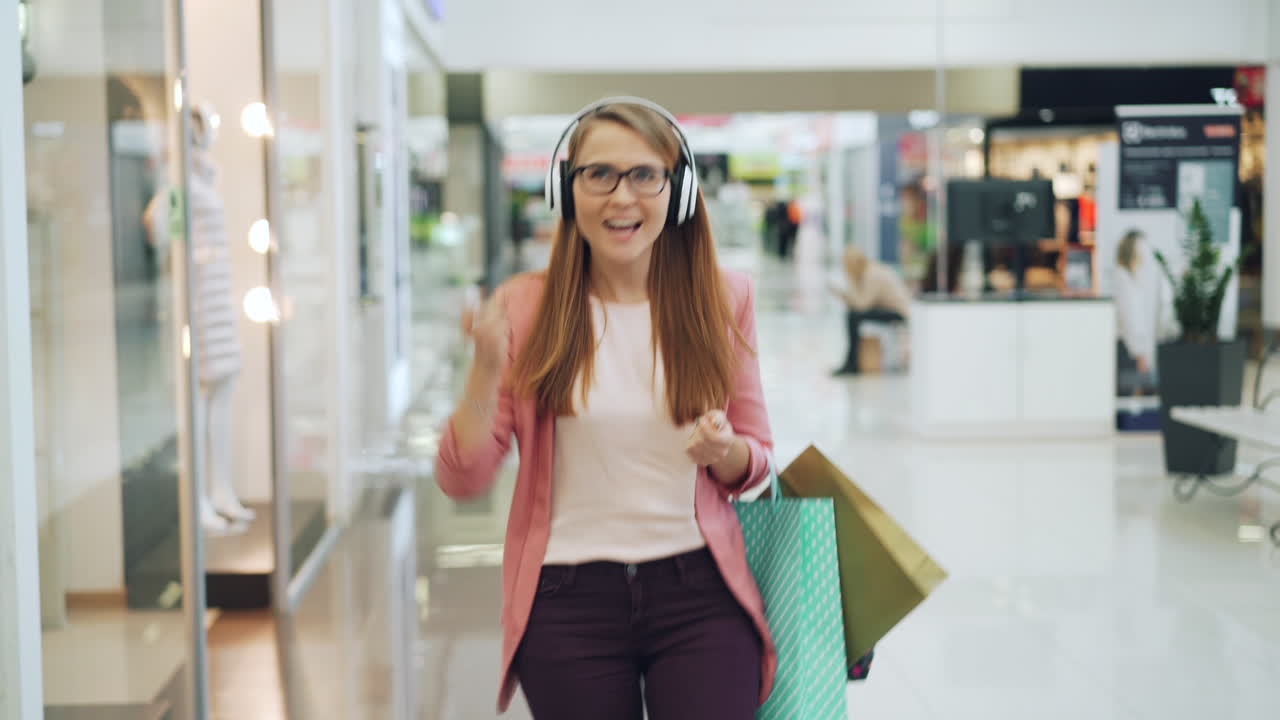 Happy Woman Shopping and Listening to Music in a Mall