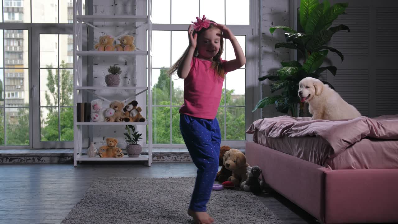 Graceful child dancing for puppy sitting on bed