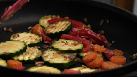 static slow motion shot of cooking delicious vegetables with zuchini, peppers, onions, garlic and carrots in hot pan in kitchen