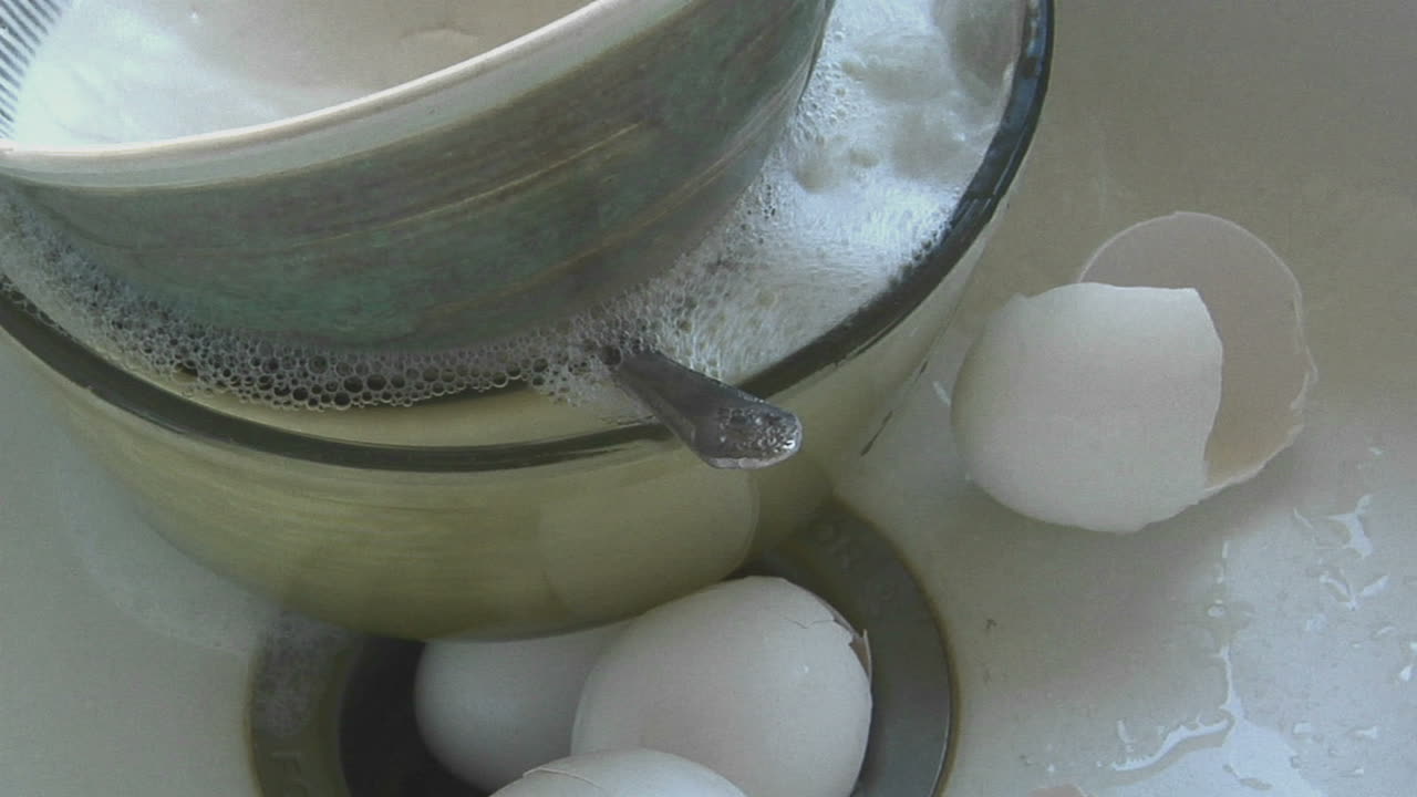 더러운 접시와 달걀 껍질이 있는 싱크대로 물이 흘러 들어갑니다.