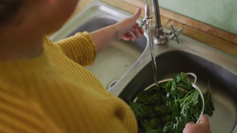 Caucasian-woman-washing-vegetables-in-kitchen