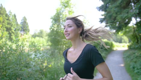 A-pretty-woman-jogging-in-a-park,-smiling-and-enjoying-the-scenery-as-she-runs