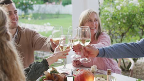 video of happy caucasian parents and grandparents making a toast at outdoor family dinner table