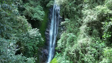 drone shot pushing in towards narrow waterfall in forest