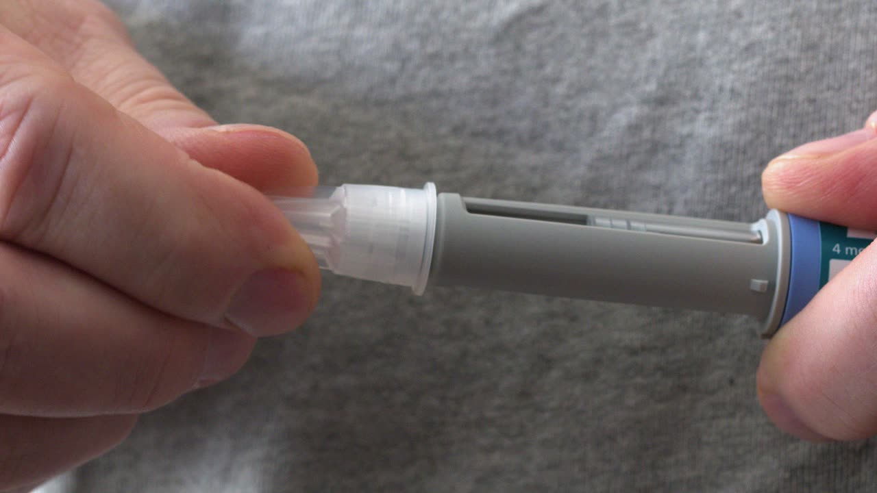 Closeup macro: Needle tip is screwed into medication injection pen
