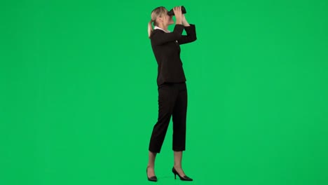 mujer de negocios mirando a través de binoculares contra la pantalla verde