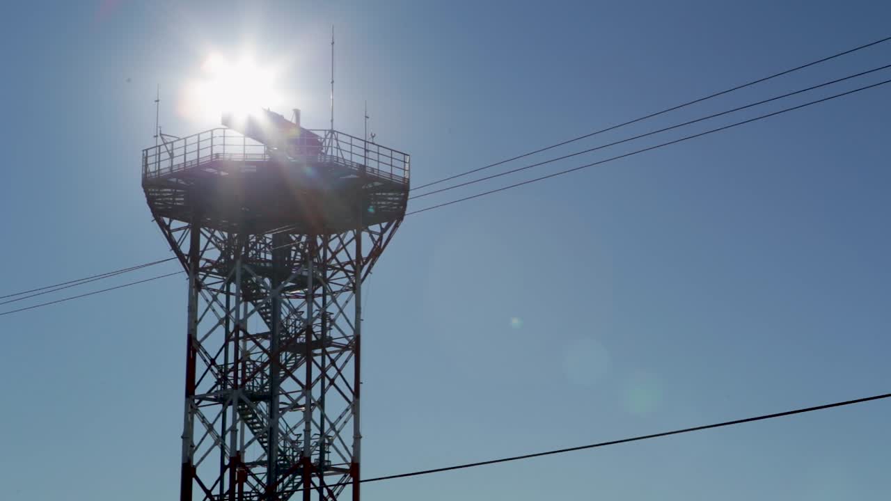 Backlit view of a communications tower against a clear blue sky, in an airport in Argentina