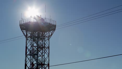 vista retroiluminada de una torre de comunicaciones contra un cielo azul claro, en un aeropuerto de argentina
