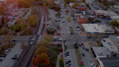 Aerial-of-train-station-in-Kirkwood,-Missouri-at-sunset-in-the-Fall-with-a-tilt-up-to-the-horizon